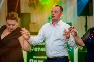 Dancers moving in sync at a formal celebration with colorful lighting effects.