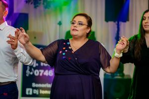 Party guests dancing under purple and green lighting at a formal celebration.