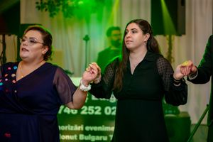 People dancing and celebrating at an indoor event with dramatic green lighting effects.