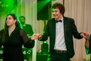 Formal event attendees dancing and having fun under theatrical green lighting.