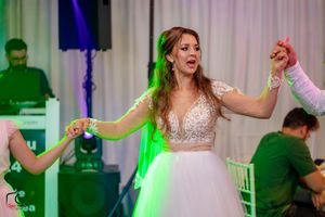 People dancing in formal attire at an event with dramatic green and blue lighting effects.