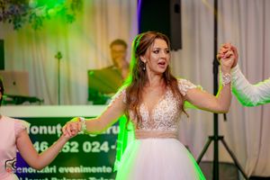 Wedding party dancing and celebrating with dramatic lighting effects in reception tent.
