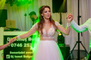 Wedding celebration with bride and guests dancing under festive green lighting.