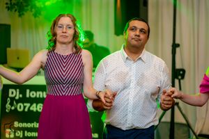 Guests enjoying dance moves at a wedding reception under green and blue mood lighting.