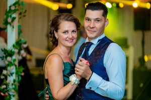 Couples dancing together at an elegant indoor wedding venue with ambient green lighting.