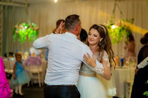 Couples sharing intimate dances at an indoor wedding reception with decorative lighting.