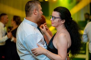 Dance partners embracing during a social dance in a warmly lit indoor venue.