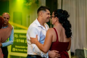 Couples dancing at an evening event with atmospheric green lighting.
