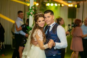 A couple sharing their first dance at a wedding reception with decorative lighting.