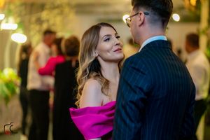 Couple in formal attire sharing an intimate moment at an elegantly lit indoor event.