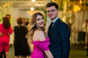A couple in formal attire dancing at an elegant event with a pink dress and pinstriped suit.