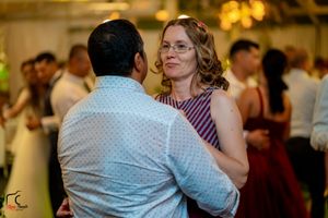 Couples slow dancing at an indoor reception with warm lighting and white drapes.
