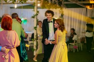 Couples dancing at an elegant indoor reception with white drapes and botanical decorations.