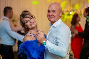 Wedding guests dancing in a reception hall with warm lighting and joyful expressions.