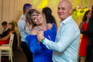 A couple dances together at a wedding reception with colorful lighting and festive atmosphere.