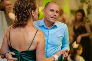 Dance partners moving together at a festive wedding celebration with green accent lighting.