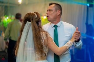 Wedding celebration with couples dancing under atmospheric blue and green lighting.