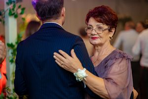 Dance partners moving gracefully across the reception floor under colorful ambient lighting.