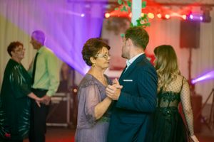 Couples slow dancing under vibrant purple and red lighting at a formal event.