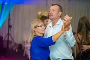 Couples dancing under blue lighting at an elegant indoor wedding reception.
