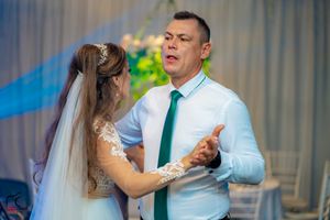 Wedding guests dancing in pairs during an evening reception with colorful lighting.
