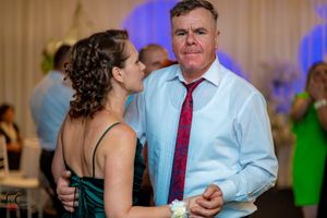 Couples slow dancing at an evening reception with blue ambient lighting.