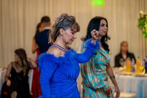 Woman in royal blue dress dancing enthusiastically at wedding reception.