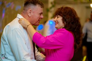 Dancing couple at wedding reception with woman in fuchsia and man in light blue shirt.