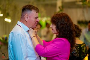 Couple sharing an intimate dance moment at wedding reception with woman in vibrant pink.