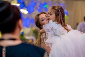 Joyful wedding reception moment with bride and young girl sharing an affectionate embrace.