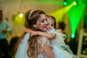 A tender moment captured at a wedding reception with colorful green and yellow lighting effects.