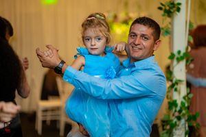 A tender dance moment at a wedding reception with a light blue suit and warm ambient lighting.