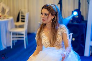 Close-up shot of bride in lace wedding gown under dramatic blue lighting at reception.