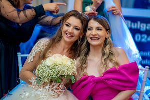 Wedding party members in formal attire celebrating at reception under decorative lighting.