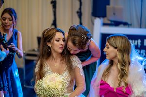 Wedding party members dancing and having fun at an indoor reception with blue mood lighting.