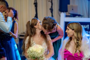 Wedding celebration with guests dancing under blue lighting in a reception hall.
