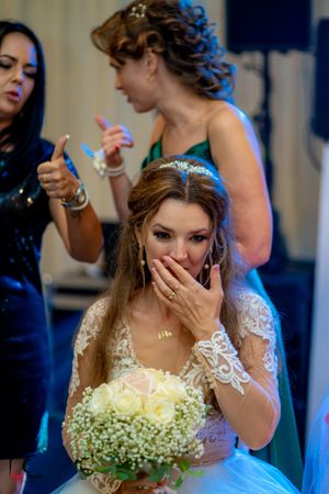Emotional wedding moment captured with bride in lace dress and floral arrangement.