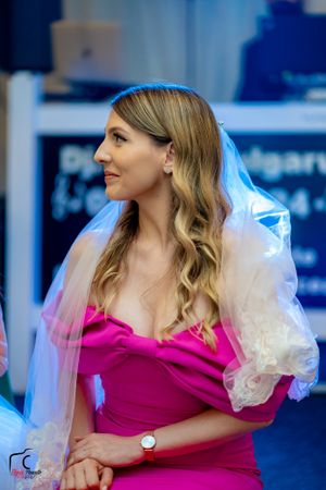 Woman in bright pink dress with puffy tulle sleeves at formal event.