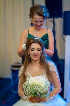 Bride in an embellished white gown holds a baby's breath bouquet during wedding celebrations.