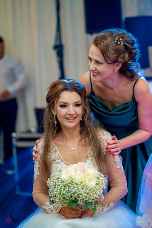 A bride in a lace wedding dress with baby's breath bouquet smiles during a wedding reception.