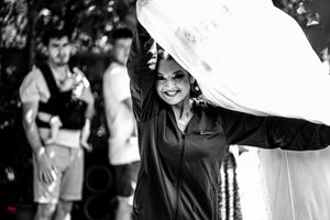A black and white photo shows someone holding up a flowing white fabric outdoors.
