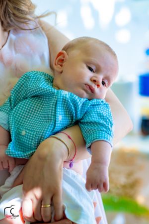 A small child in turquoise clothing rests peacefully during wedding preparations.