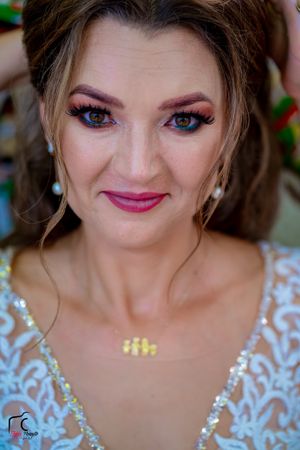 Close-up portrait highlighting bridal makeup and delicate white lace wedding dress details.