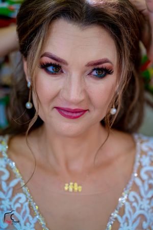 Wedding day beauty shot with pink lips, dramatic eyes and ornate white lace details.
