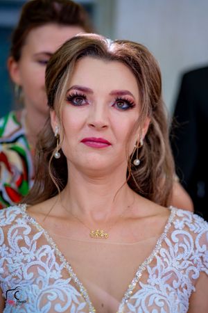 Elegant bridal close-up with pink lipstick, pearl earrings and detailed white lace gown.
