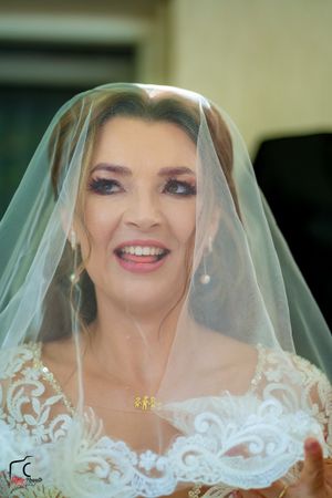 Joyful bride smiling while wearing a detailed lace wedding dress and classic veil.