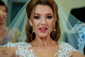 Close-up portrait of a bride wearing an ornate lace wedding gown with a flowing veil.