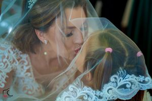 A bride in a delicate white lace dress and veil poses during her wedding day.