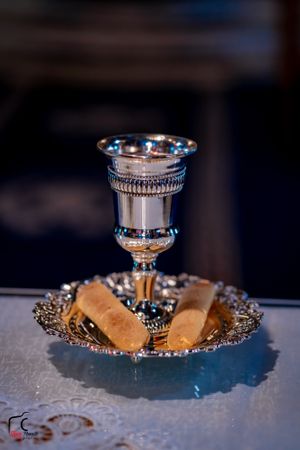 Silver communion chalice and bread pieces on an ornate metallic plate during ceremony.
