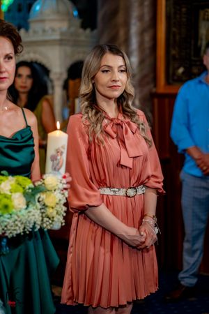 Attendee in flowing coral dress standing near floral arrangements and candles.